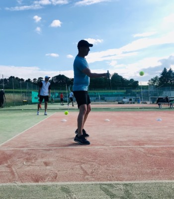 Homme tapant dans une balle sur un court de tennis en extérieur
