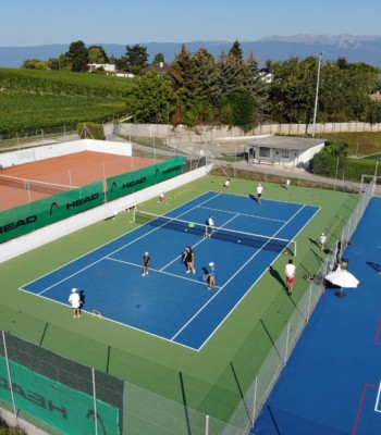 Court de tennis au soleil, avec plusieurs joueurs se préparant à commencer un match
